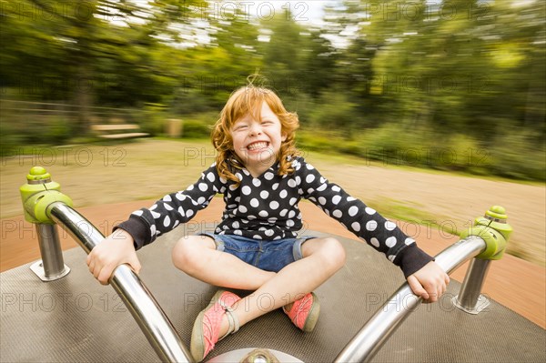 Caucasian girl playing on merry-go-round