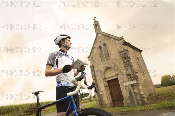 Caucasian cyclist reading map near church