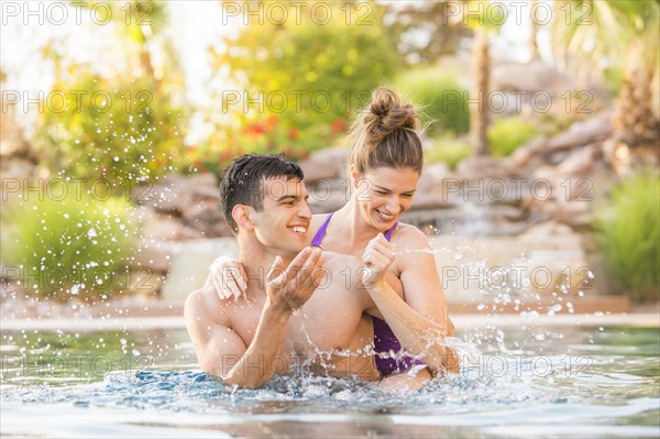 Couple splashing in swimming pool