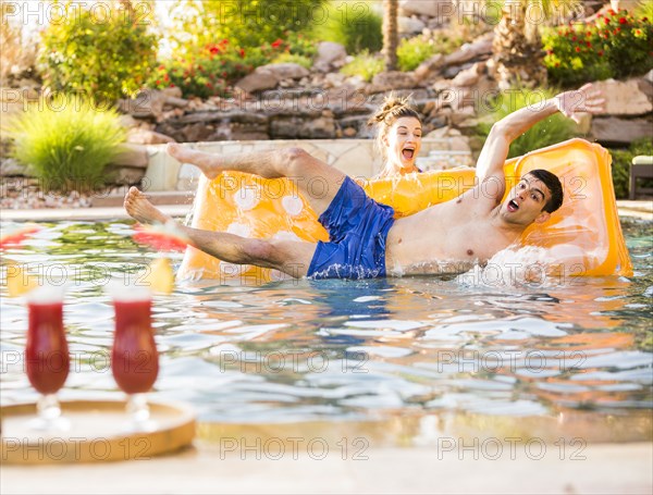 Woman pushing boyfriend in swimming pool