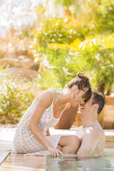 Caucasian couple whispering in swimming pool