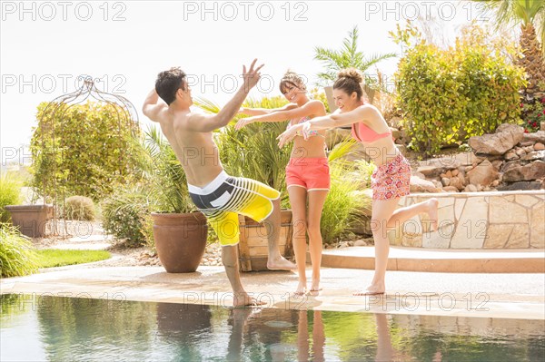 Women pushing man into swimming pool