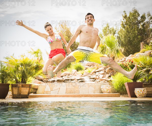 Couple jumping into swimming pool