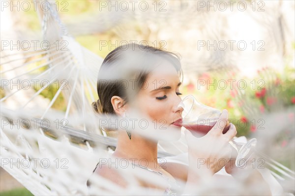 Caucasian woman drinking cocktail in hammock