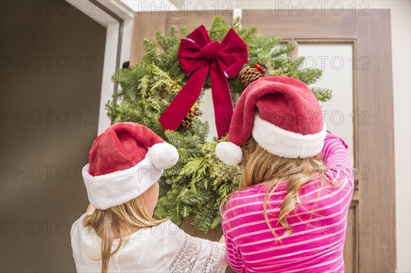 Caucasian girls hanging Christmas wreath