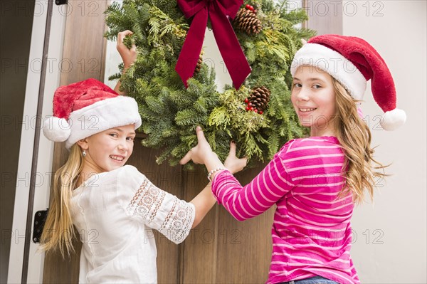 Caucasian girls hanging Christmas wreath