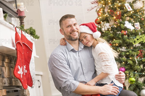 Caucasian father and daughter hugging near Christmas tree