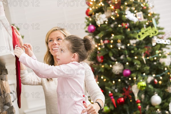 Caucasian mother and daughter hanging Christmas stockings