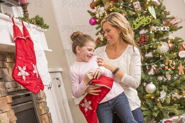 Caucasian mother and daughter hanging Christmas stockings