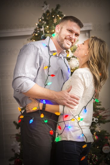 Caucasian couple wrapped in Christmas lights