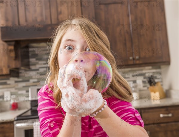 Caucasian girl blowing soap bubble
