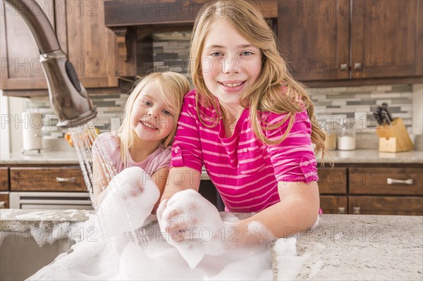 Caucasian girls washing hands in kitchen sink