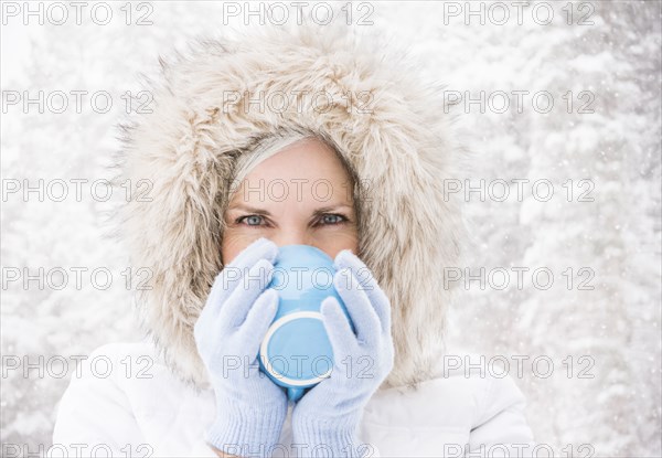 Caucasian woman drinking coffee in snow