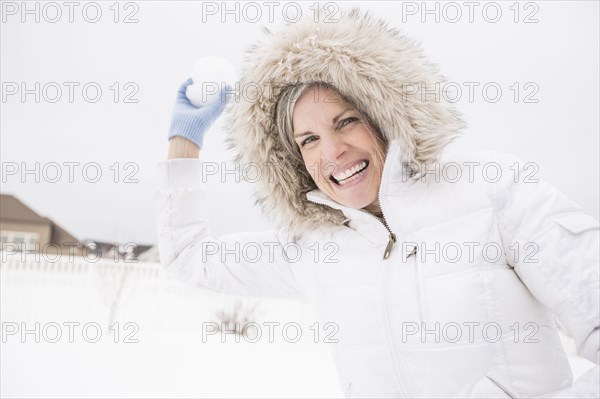 Caucasian woman throwing snowball in snow