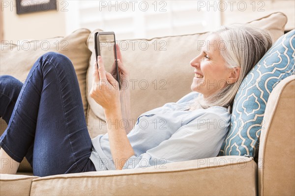 Caucasian woman using digital tablet on sofa