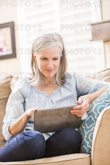 Caucasian woman using digital tablet on sofa