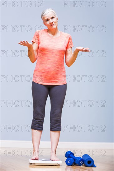 Caucasian woman shrugging on yoga mat