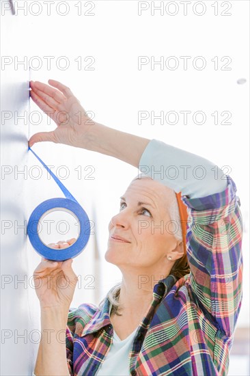 Caucasian woman taping off painting area