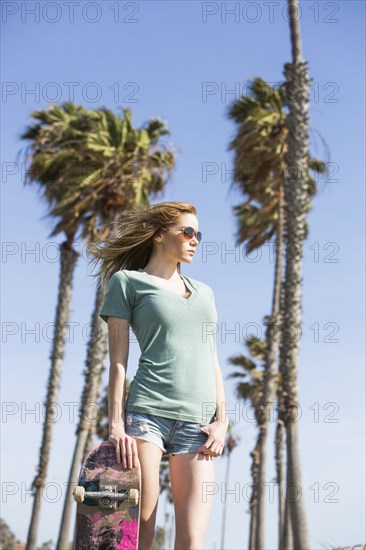 Caucasian woman holding skateboard outdoors