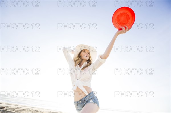 Caucasian woman holding plastic disc on beach