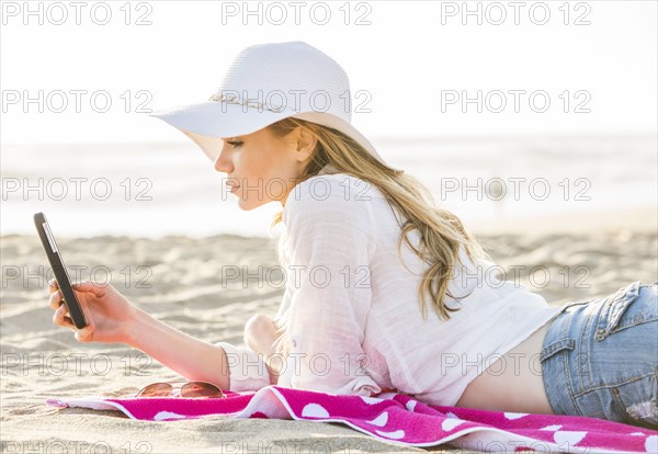 Caucasian woman using cell phone on beach