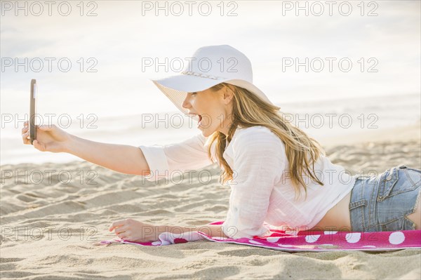 Caucasian woman using cell phone on beach