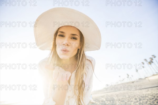 Caucasian woman blowing kiss on beach