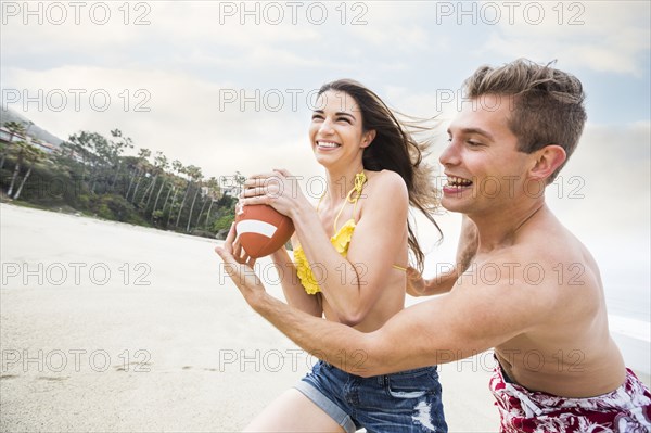 Caucasian couple playing on beach