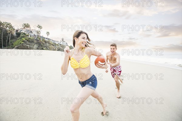 Caucasian couple playing on beach