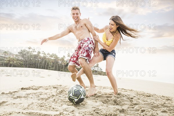 Caucasian couple playing on beach
