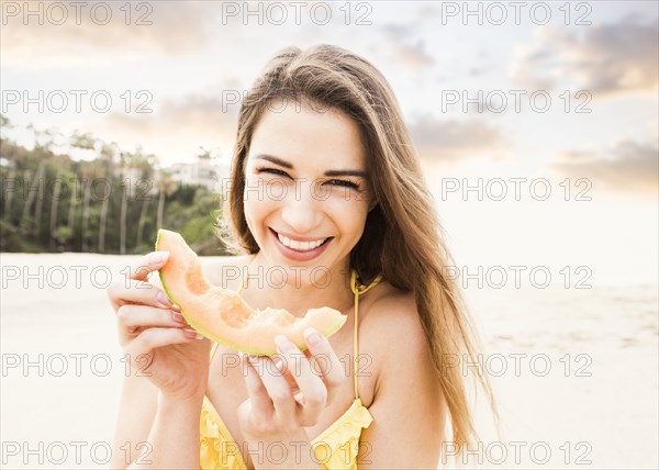 Caucasian woman eating fruit on beach