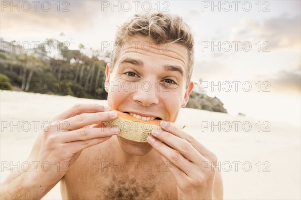 Caucasian man eating fruit on beach