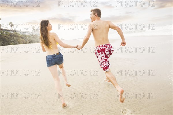 Caucasian couple running on beach