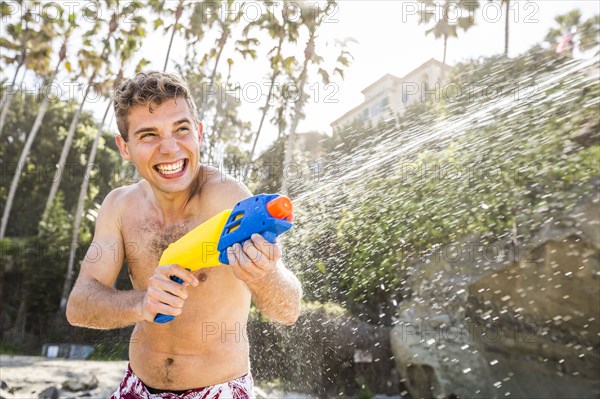 Caucasian couple playing with squirt guns on beach