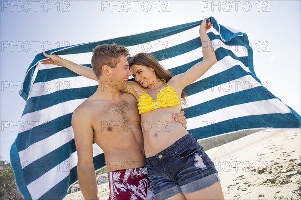 Caucasian couple holding towel on beach