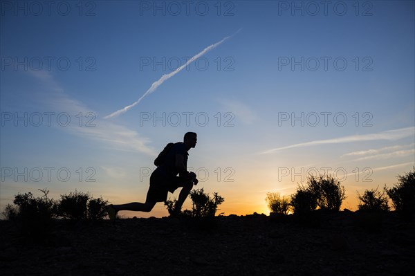 Silhouette of Caucasian teenage boy running at dawn