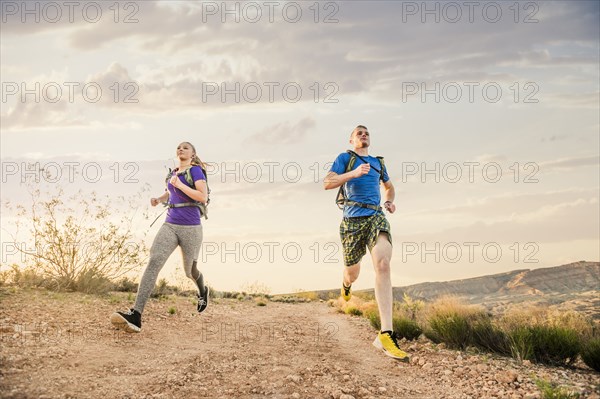 Caucasian couple running on remote hilltop