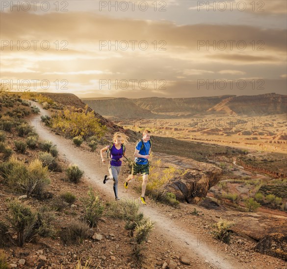 Caucasian couple running on remote dirt path
