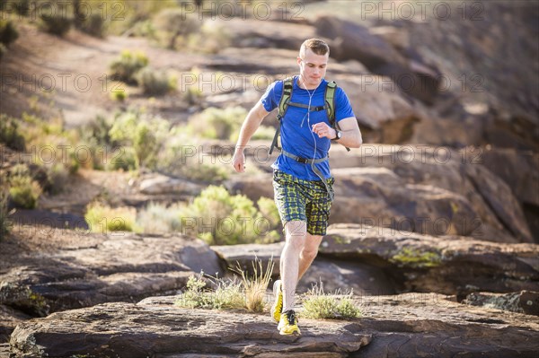 Caucasian teenage boy running on rock formation