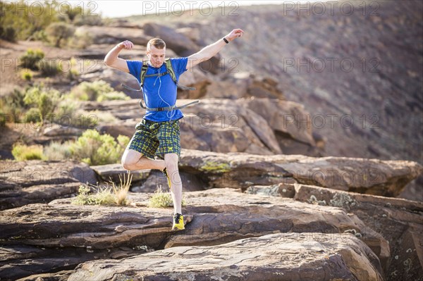 Caucasian teenage boy running on rock formation