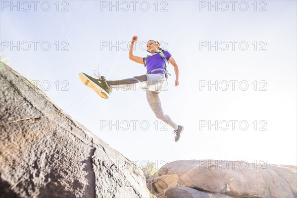 Caucasian woman leaping over boulders