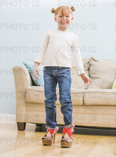 Caucasian girl wearing adult shoes in living room