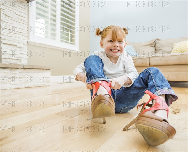Caucasian girl wearing adult shoes in living room