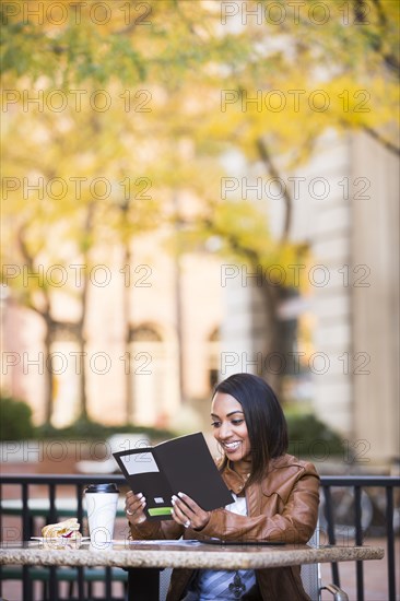 Indian woman reading booklet at outdoor cafe