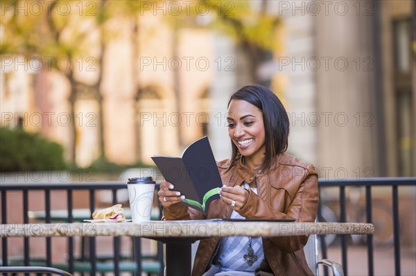 Indian woman reading booklet at outdoor cafe
