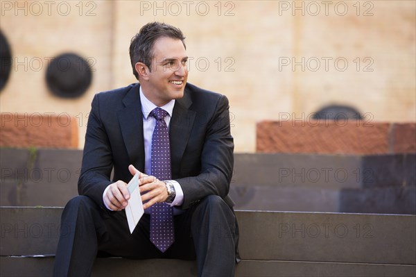 Caucasian businessman sitting on staircase holding paperwork