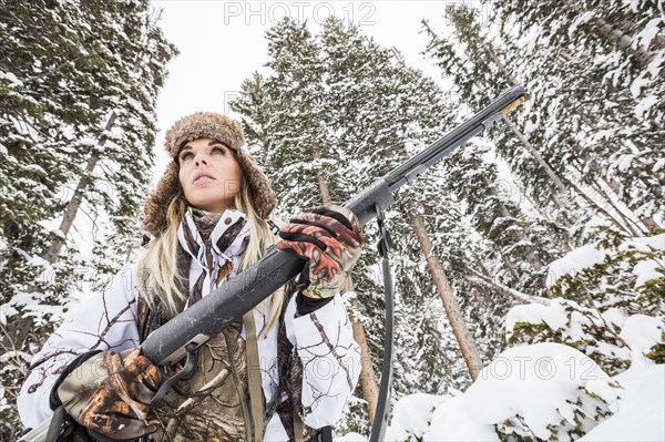 Caucasian woman hunting in forest holding rifle