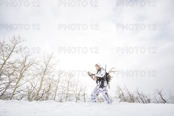 Caucasian woman hunting in forest texting on cell phone