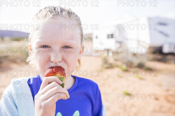 Caucasian girl biting strawberry