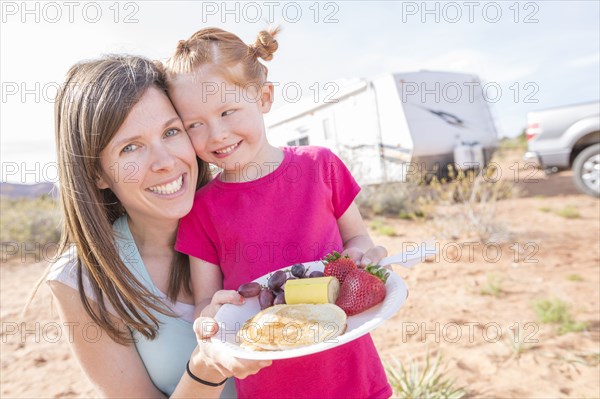 Caucasian mother and daughter posing with breakfast plate